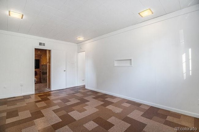 spare room featuring dark carpet and ornamental molding