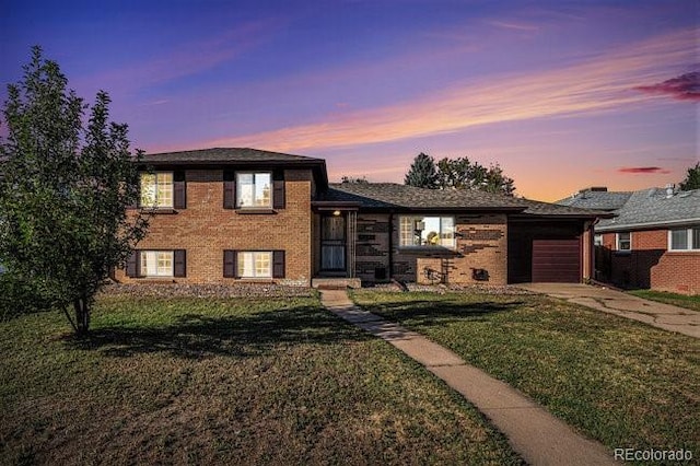 tri-level home featuring a garage and a lawn