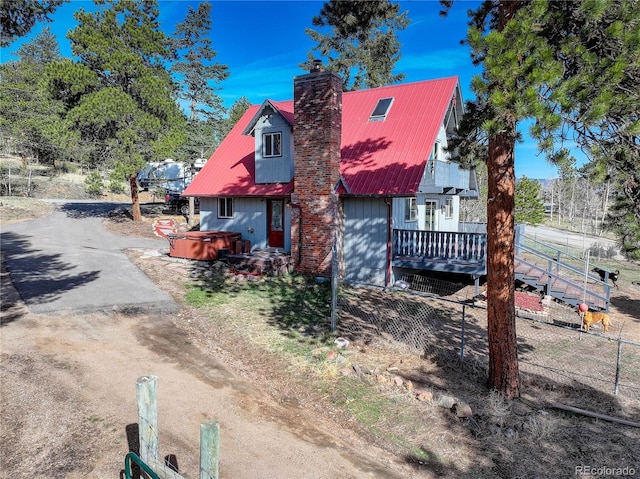 952 Burland Dr, Bailey, CO 80421 - view of front facade featuring a hot tub, a chimney, a deck, metal roof, and dirt driveway