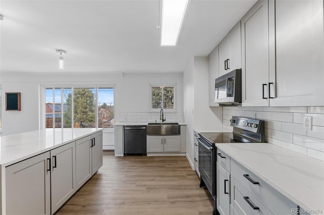 4731 W 66th Ave, Arvada, CO 80003 - kitchen with stainless steel appliances, a sink, tasteful backsplash, light wood-style floors, and light stone countertops