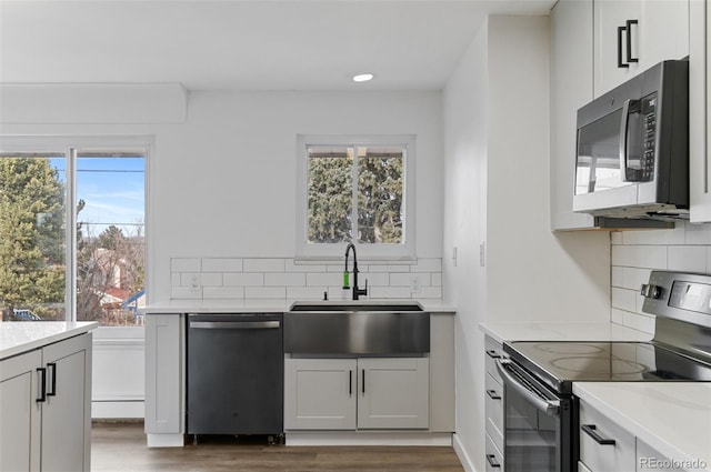 4731 W 66th Ave, Arvada, CO 80003 - kitchen featuring appliances with stainless steel finishes, a sink, wood finished floors, tasteful backsplash, and recessed lighting
