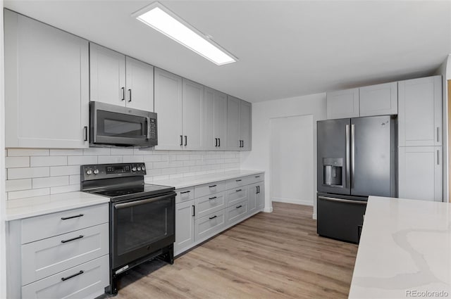 4731 W 66th Ave, Arvada, CO 80003 - kitchen with stainless steel appliances, tasteful backsplash, light wood-type flooring, baseboards, and light stone countertops