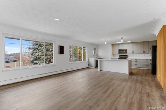 4731 W 66th Ave, Arvada, CO 80003 - unfurnished living room with wood finished floors, a baseboard heating unit, recessed lighting, and a sink