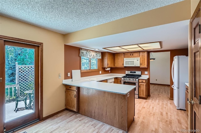 20596 E Shefield Ct, Parker, CO 80138 - kitchen with white appliances, a peninsula, brown cabinets, light wood-style floors, and light countertops