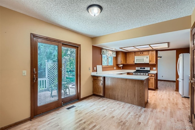20596 E Shefield Ct, Parker, CO 80138 - kitchen with white appliances, brown cabinets, a peninsula, light wood-style flooring, and a textured ceiling