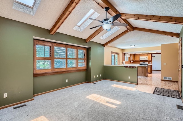 20596 E Shefield Ct, Parker, CO 80138 - unfurnished living room featuring a skylight, light carpet, beamed ceiling, a ceiling fan, and a textured ceiling