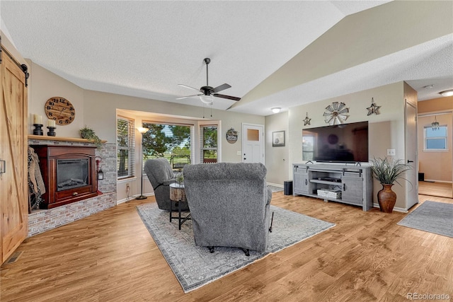 living room featuring visible vents, ceiling fan, light wood finished floors, and vaulted ceiling