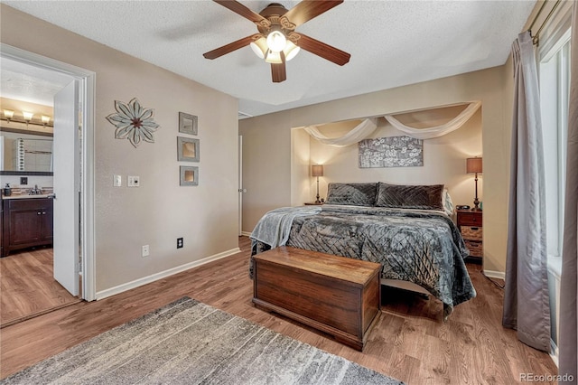 bedroom featuring ceiling fan, connected bathroom, a sink, light wood finished floors, and baseboards
