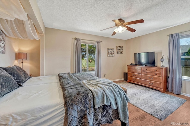 bedroom with light wood-style flooring, a ceiling fan, baseboards, and a textured ceiling