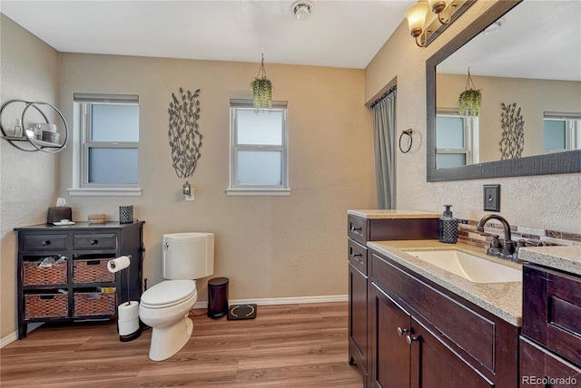 bathroom featuring wood finished floors, a textured wall, baseboards, and vanity