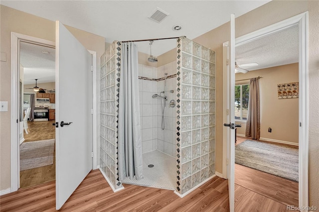 bathroom featuring a tile shower, wood finished floors, and a ceiling fan