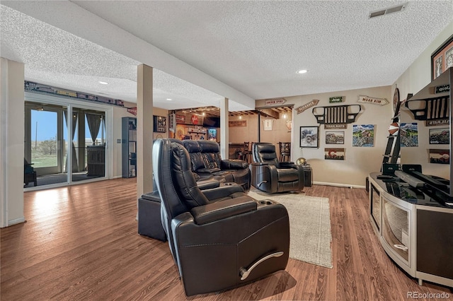 living room featuring recessed lighting, visible vents, a textured ceiling, and wood finished floors