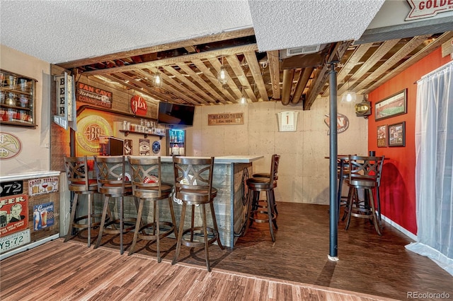 bar with visible vents, a dry bar, and wood finished floors