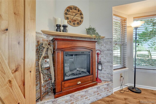 room details with wood finished floors, baseboards, and a glass covered fireplace