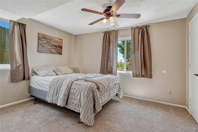 carpeted bedroom featuring a textured ceiling, baseboards, and ceiling fan