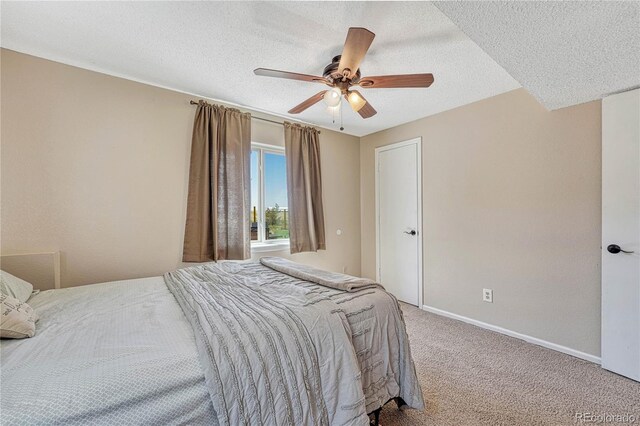 carpeted bedroom with baseboards, ceiling fan, and a textured ceiling