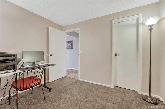 carpeted office featuring baseboards and a textured ceiling