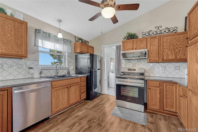 kitchen featuring a ceiling fan, vaulted ceiling, a sink, stainless steel appliances, and backsplash