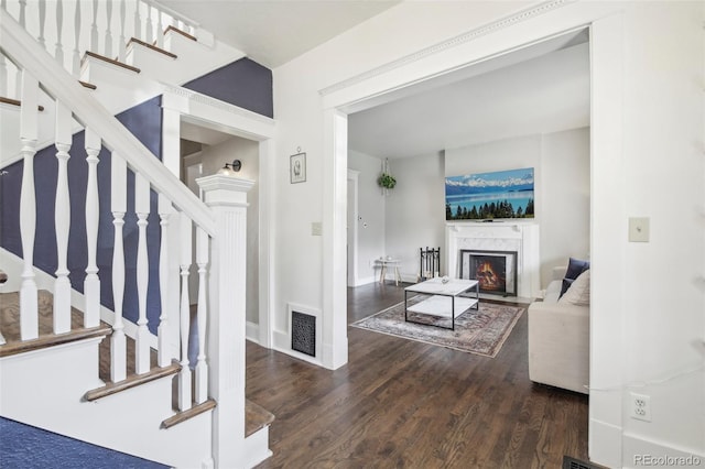 living room featuring a premium fireplace, wood finished floors, stairs, and baseboards