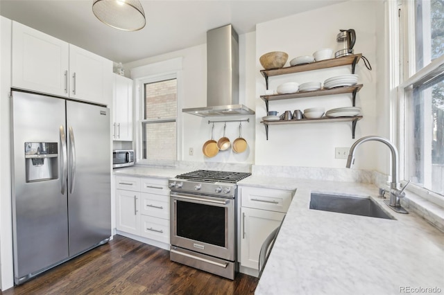 kitchen with appliances with stainless steel finishes, wall chimney exhaust hood, a sink, open shelves, and white cabinets