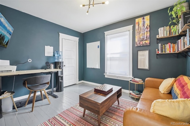 living area featuring a desk, baseboards, wood finished floors, and a chandelier