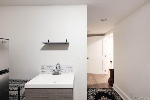 bathroom with baseboards, wood finished floors, vanity, and recessed lighting