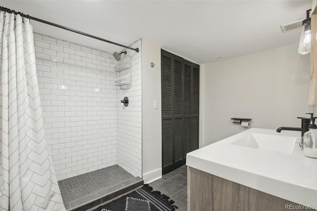 bathroom featuring tiled shower, tile patterned floors, vanity, and a closet
