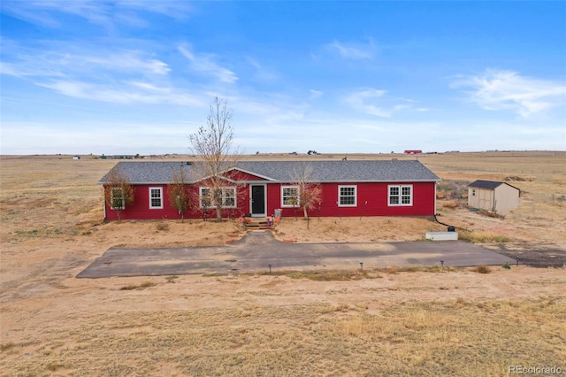 ranch-style home with a rural view and a storage unit