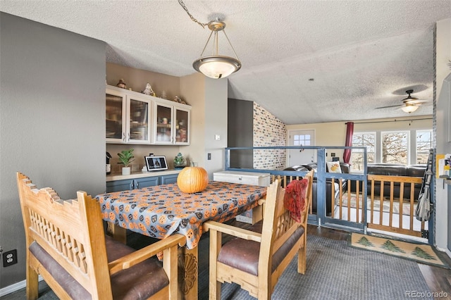 dining space with dark wood-type flooring, ceiling fan, a textured ceiling, and lofted ceiling