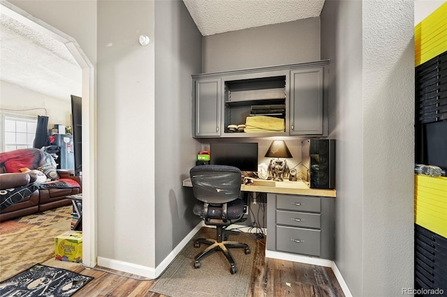 office space featuring built in desk, a textured ceiling, and hardwood / wood-style floors