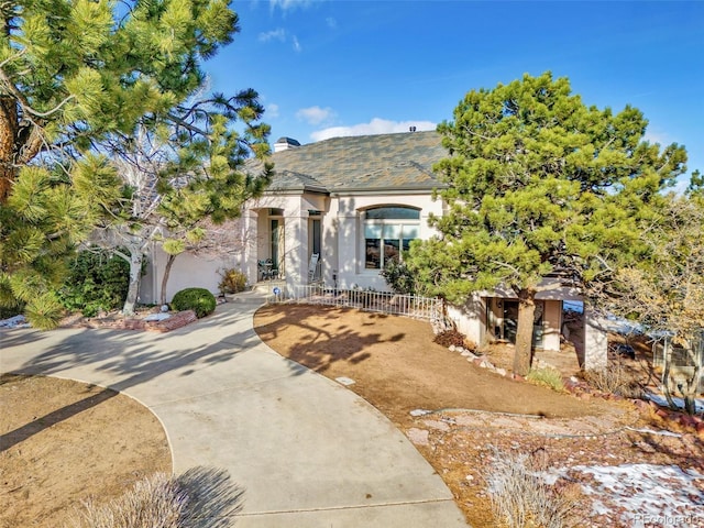 view of front of house featuring a fenced front yard, a chimney, and stucco siding