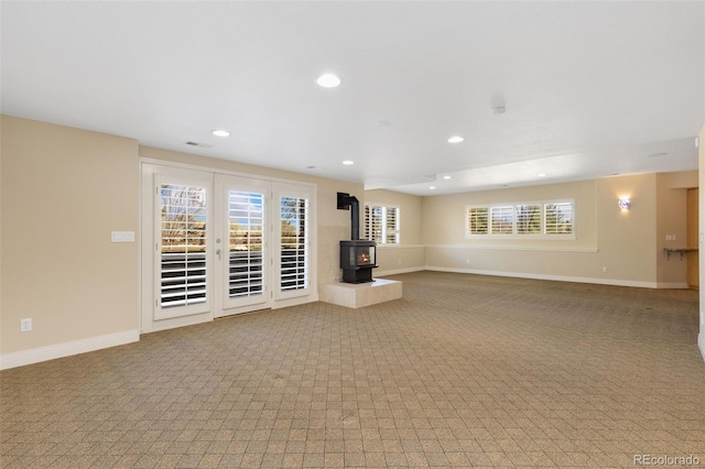 unfurnished living room with a wood stove, recessed lighting, visible vents, and carpet floors