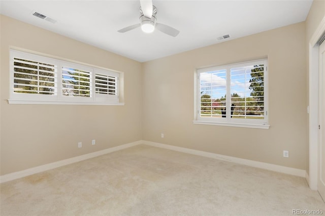 carpeted empty room featuring baseboards, visible vents, and a ceiling fan