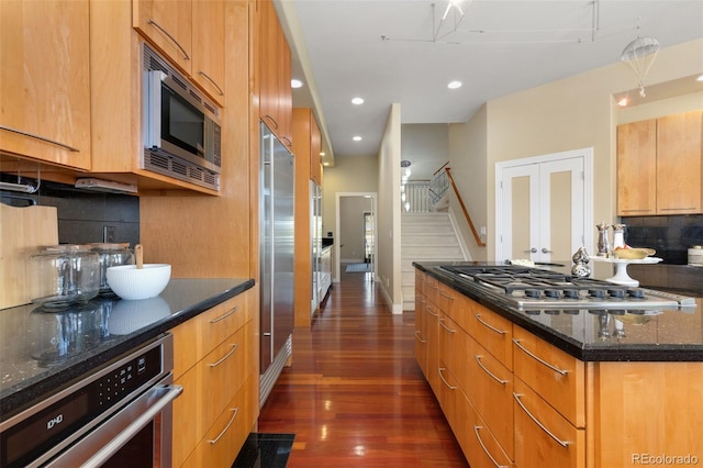 kitchen featuring dark stone counters, dark wood-style floors, backsplash, appliances with stainless steel finishes, and recessed lighting