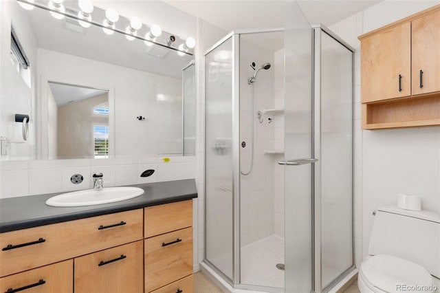 bathroom featuring toilet, vanity, and a shower stall
