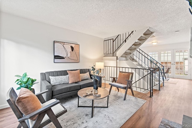 living room with wood finished floors, stairway, a textured ceiling, and french doors