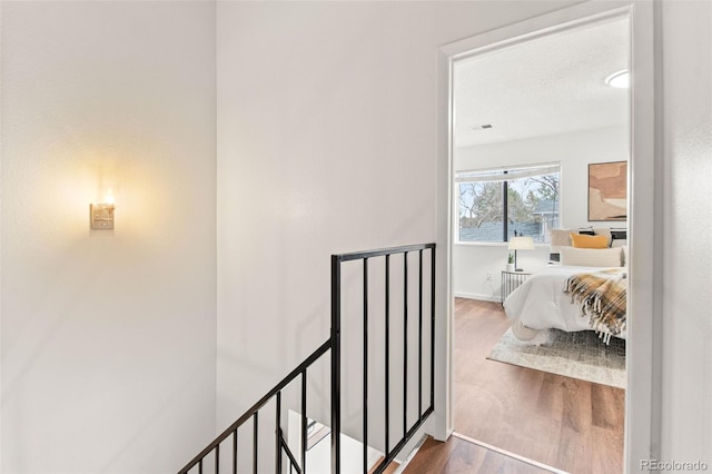 hallway featuring an upstairs landing, wood finished floors, and baseboards