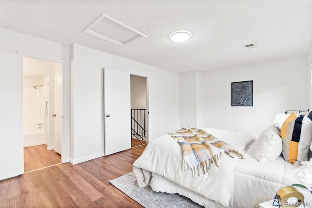 bedroom featuring attic access, wood finished floors, and a textured ceiling