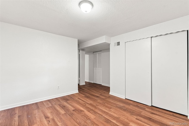 unfurnished bedroom with light wood-type flooring, baseboards, a textured ceiling, and a closet
