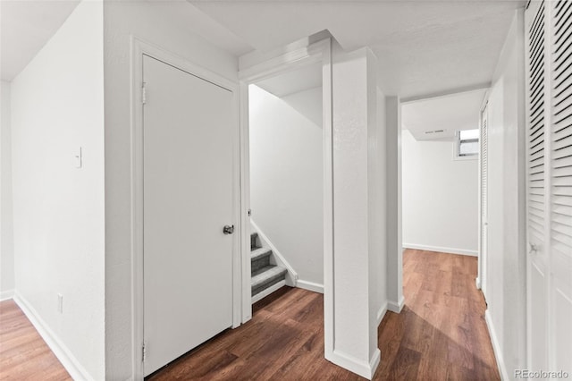 hallway with wood finished floors, stairway, and baseboards