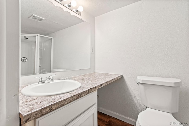bathroom featuring toilet, wood finished floors, a shower stall, vanity, and baseboards
