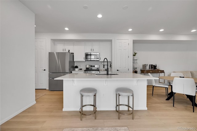 4612 S Wenatchee St Unit A, Aurora, CO 80015 - kitchen with appliances with stainless steel finishes, a breakfast bar, light wood-style floors, recessed lighting, and light countertops