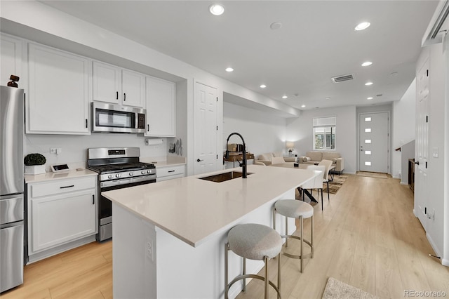 4612 S Wenatchee St Unit A, Aurora, CO 80015 - kitchen featuring appliances with stainless steel finishes, open floor plan, recessed lighting, light wood finished floors, and an island with sink