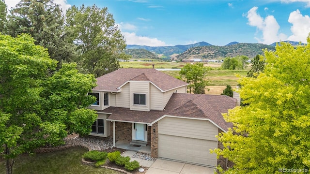 6005 S Vivian St, Littleton, CO 80127 - view of front of property featuring a shingled roof, a garage, a mountain view, concrete driveway, and brick siding