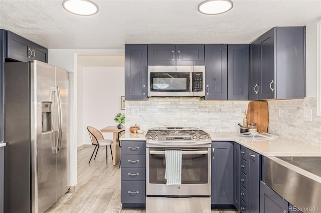 6005 S Vivian St, Littleton, CO 80127 - kitchen featuring appliances with stainless steel finishes, light countertops, decorative backsplash, light wood-style flooring, and a textured ceiling