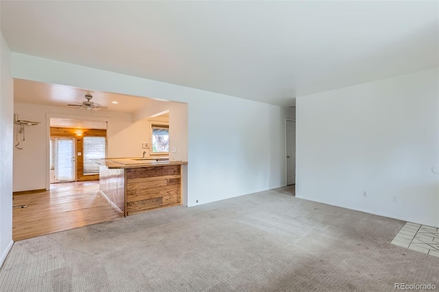 unfurnished living room featuring ceiling fan and light carpet