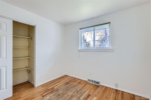 unfurnished bedroom featuring light wood finished floors, baseboards, visible vents, and a closet