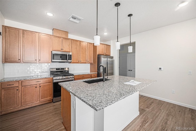 kitchen featuring appliances with stainless steel finishes, visible vents, a sink, and wood finished floors