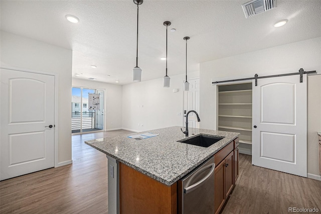 kitchen featuring a barn door, visible vents, a sink, light wood-type flooring, and stainless steel dishwasher