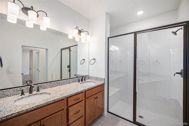 full bath with a stall shower, double vanity, a sink, and tile patterned floors